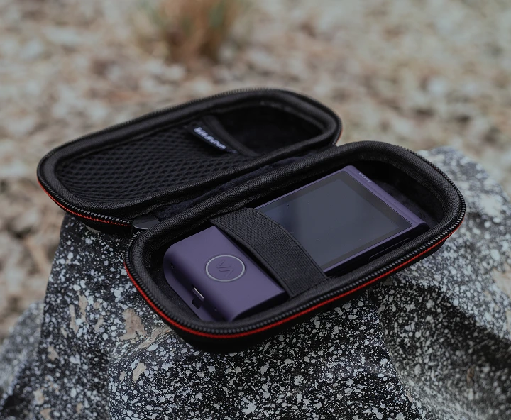 Case for the Vasco Translator M4 lying on a stone, with a purple Vasco Translator M4 device inside the case.
